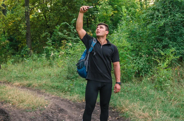 Portrait of a man traveller searching connection on the phone in the forest.