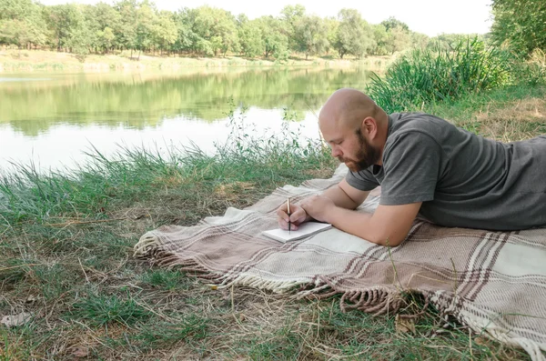 Man writing in his notebook in forest.