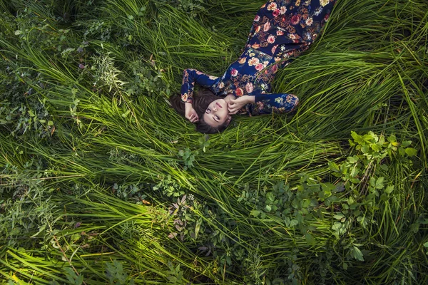 Beautiful young woman in dress lying in the grass