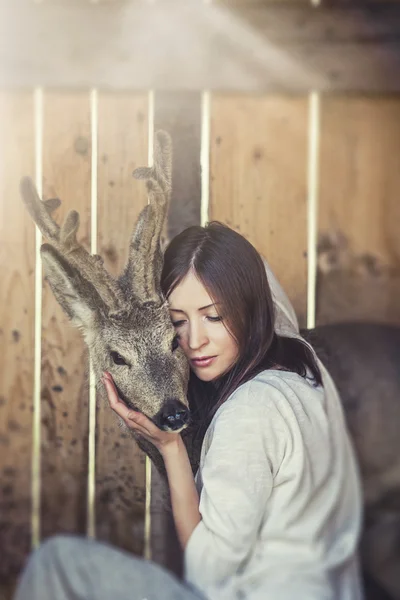 Young beautiful woman hugging animal ROE deer in the sunshine