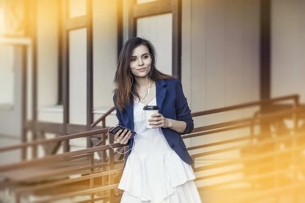Beautiful young fashion gir with take-away coffee in hand and sm