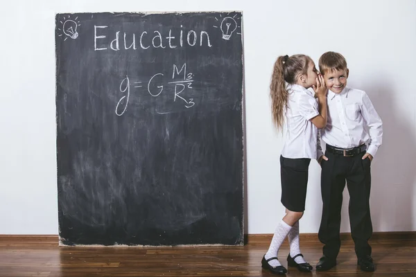 Boy and girl of elementary school in class background slate