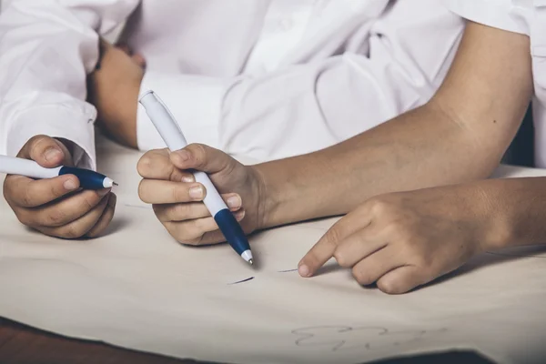 Boy and girl writing with a pen on the paper at the table closeu