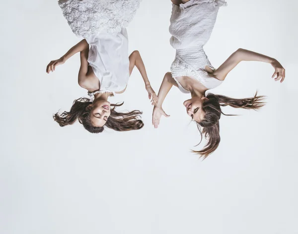 Beautiful young girls in white dresses jump high and defiantly