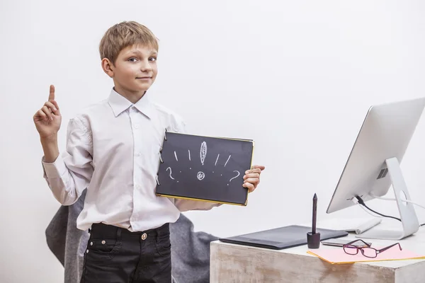 Boy child with a computer, in the office in a white shirt busine