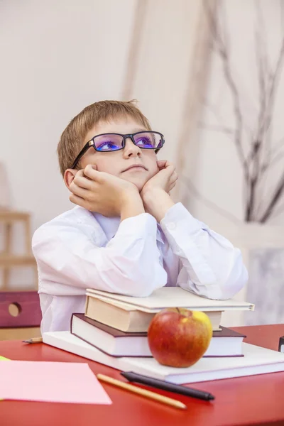 Boy, child, at school, at a school Desk with books in the glasse