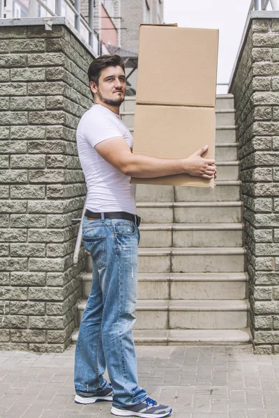 Porter, the man with cardboard boxes in the hands of a strong, d