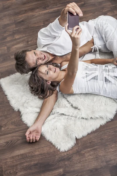 Couple man and woman taking selfies on the floor on the carpet