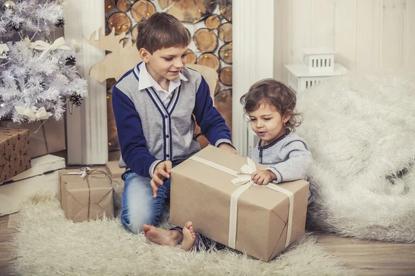Happy boy and girl with boxes of gifts in the Christmas interior