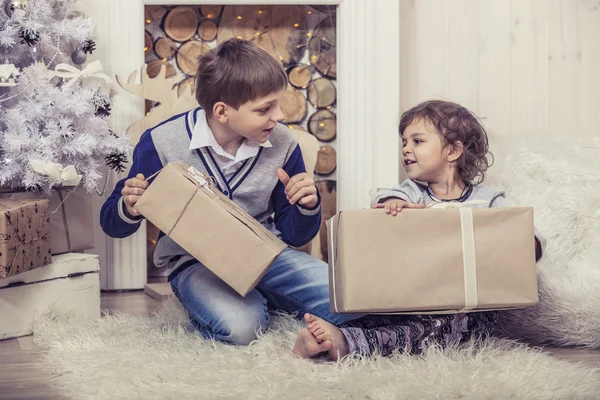Happy boy and girl with boxes of gifts in the Christmas interior