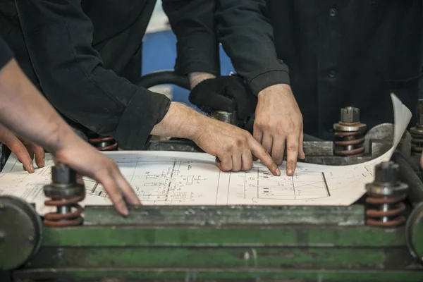 Men with drawings working in an old factory to install the equip