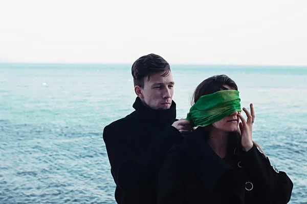 Man putting blindfold on woman\'s eyes