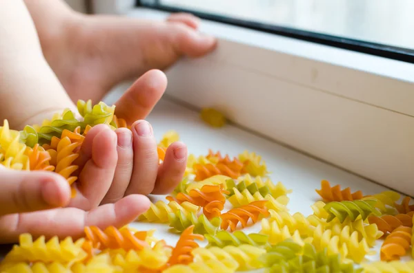 Child hands full of spiral pasta