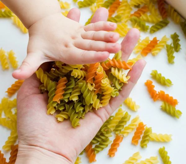 Child hands full of spiral pasta