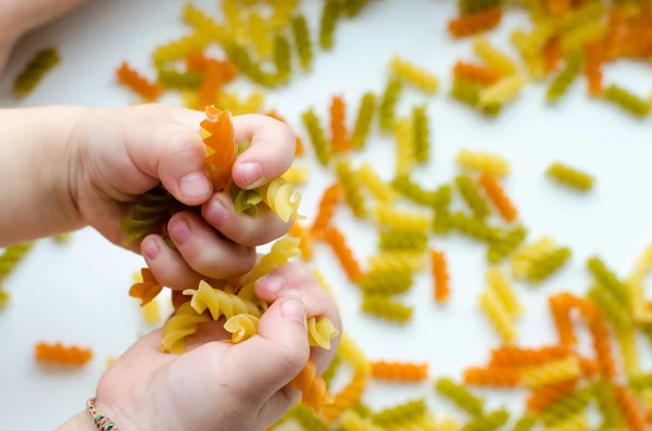 Child hands full of spiral pasta