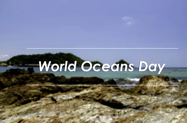 Image concept with word WORLD OCEANS DAY.blurred background Rocky shore with blue sky background