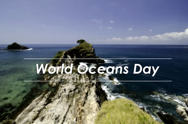 Image concept with word WORLD OCEANS DAY.blurred background view from the top hill view,tropical island surrounded by clear water and blue sky at sunny day