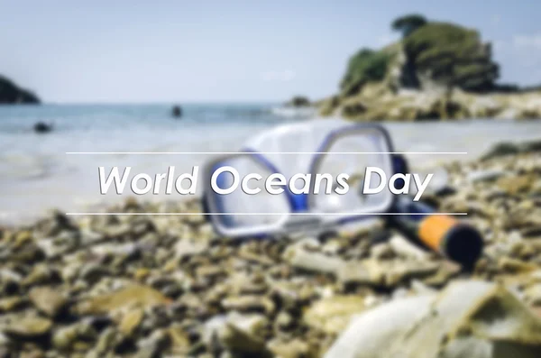 Image concept with word WORLD OCEANS DAY.blurred background retro look , image of Diving Goggles and Snorkel Gear on stone at sunny day.