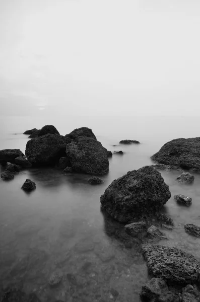 Black and white image of rock over the beach background