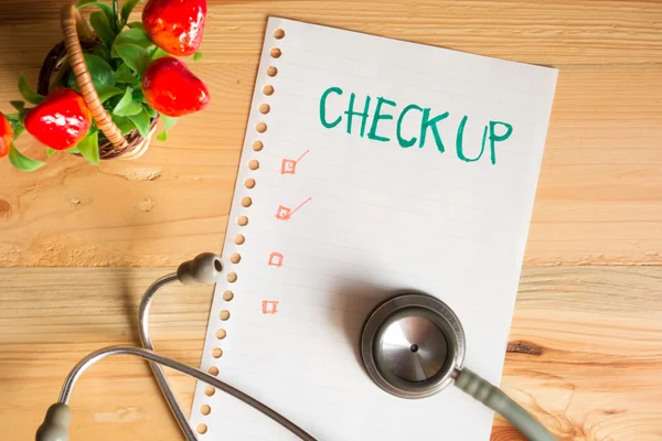 Health Check up list concept, top view of paper check list and Stethoscope on wood table , digital effect vintage style