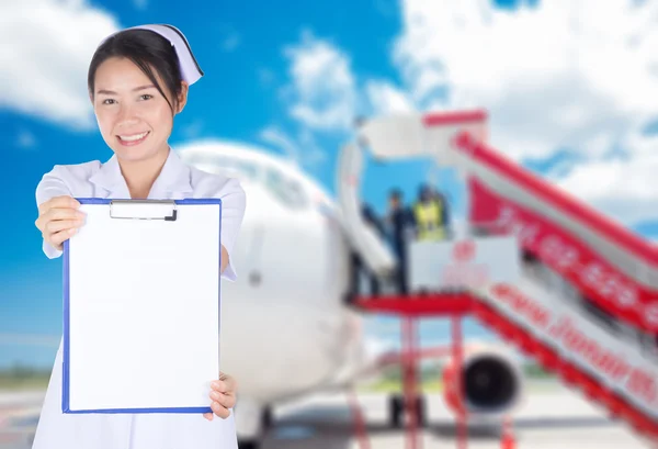 The blank board held by asian nurse with airplane in background , medical tourism concept