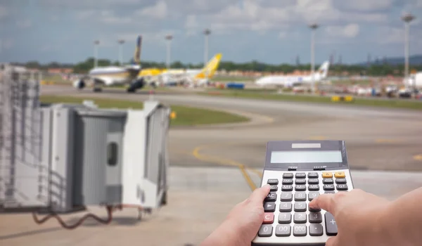 Travel cost calculation concept by calculator and runway in background