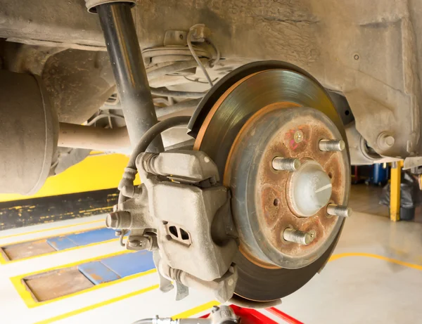 Rear disc brake on car in process of new tire replacement. The rim is removed showing the rear rotor and caliper