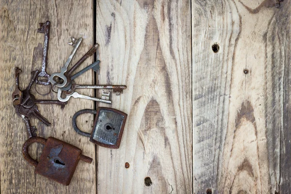 Old vintage keys and locks on antique weathered barn wood board planks.