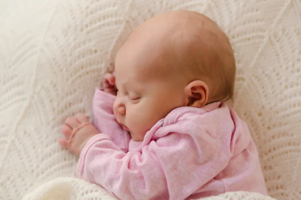 Closeup newborn baby sleeping on white blanket satisfied