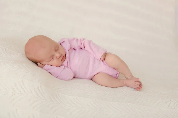 Newborn baby girl sleeping on white blanket napping