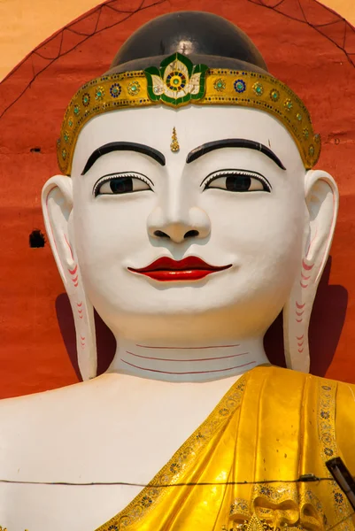 The Buddha is face closeup. Four statues of sitting Buddhas. Pagoda Kyaikpun Buddha. Bago, Myanmar. Burma.