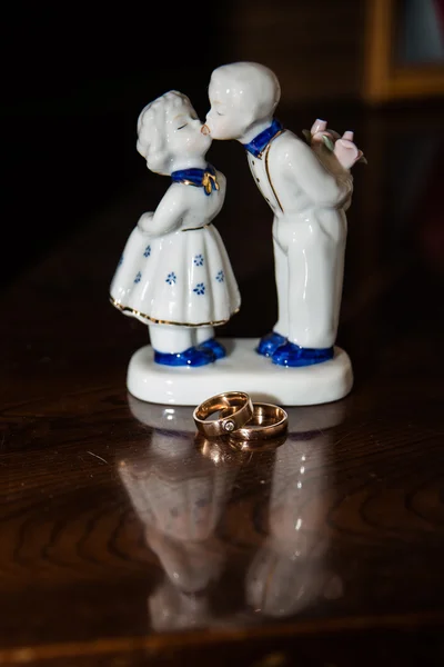 Two wedding rings.A small sculpture of a boy and girl