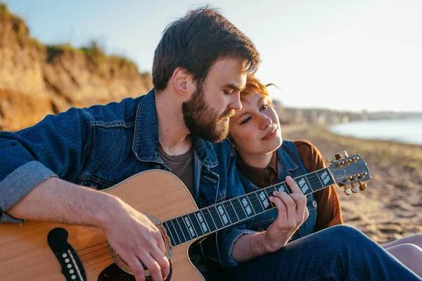 Couple playing guitar on beach