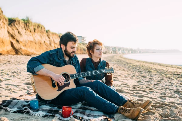 Couple playing guitar on beach