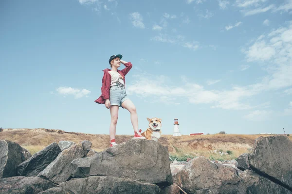 Redhead girl with welsh corgi dog on the seaside