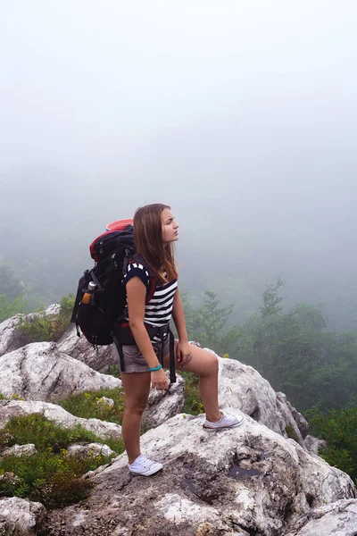 Young caucasian female hiker in mountains, woman hiking in the fog with a backpack in Crimea