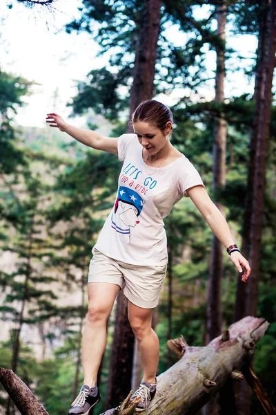 Caucasian hiker woman on trek in mountains living a healthy active lifestyle. Hiker girl on nature landscape hike in Crimea balancing on a tree, happy free female in the wood.