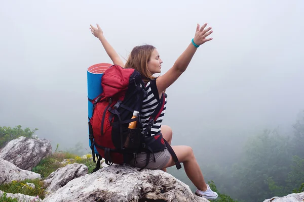 Young caucasian female hiker in mountains, woman hiking in the fog with a backpack