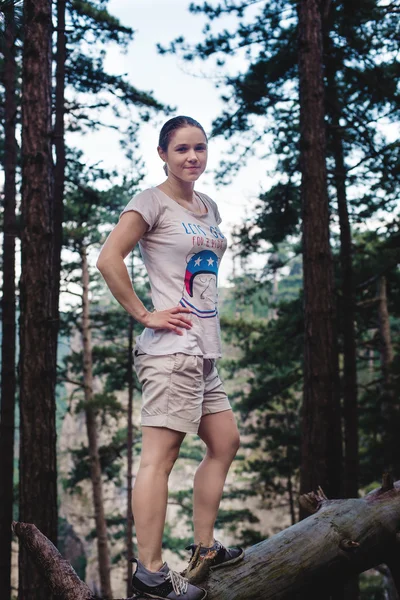 Caucasian hiker woman on trek in mountains living a healthy active lifestyle. Hiker girl on nature landscape hike in Crimea balancing on a tree, happy free female in the wood.