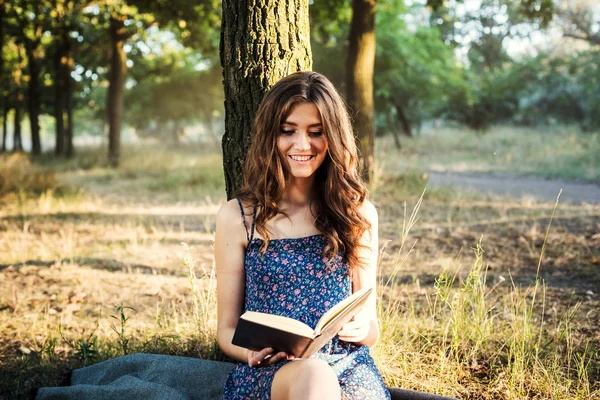 Young beautiful caucasian female reading book in park