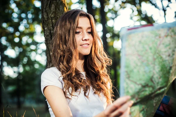 Young caucasian female with backpacks and map in wood, hiker loo