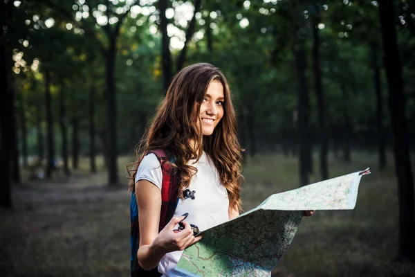 Young caucasian female with backpacks and map in wood, hiker loo
