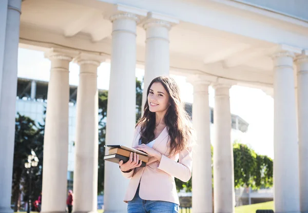 Young caucasian female student with books and tablet on campus, student study in campus area