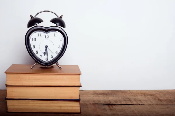 Books and alarm clock on wooden background. Education equipment, education concept