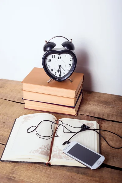 Books, alarm clock, notepad, cellphone with earphones  on wooden background. Education equipment, education concept