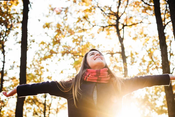 Young happy woman with cheering hands in park. Female enjoying autumn sun