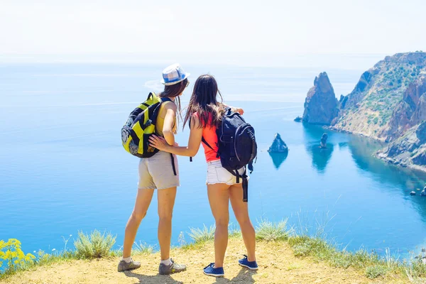 Two young caucasian females hiking on a cliff above the sea
