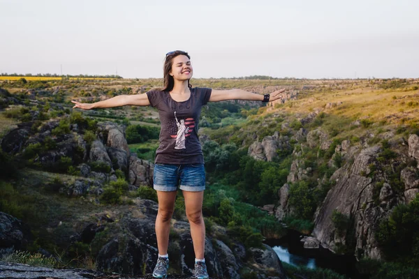 Young caucasian female jumping in canyon, girl having fun on beautiful natural landscape with rocks