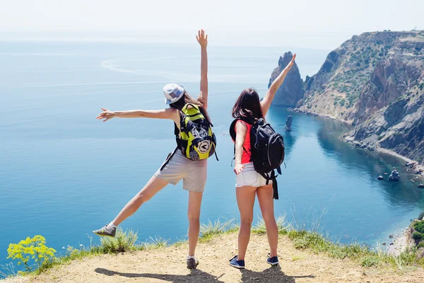 Two young caucasian females hiking on a cliff above the sea