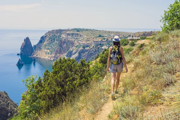 Young caucasian female hiking on a cliff above the sea